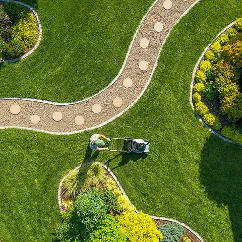 Rasenmähen im großen Garten durch kaukasischen Gärtner